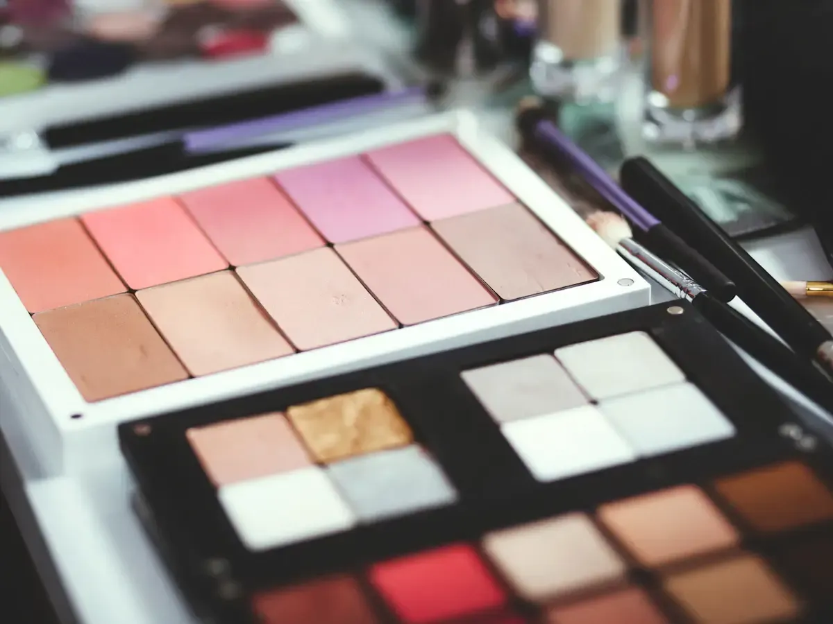 Soft-focus pink and neutral makeup palettes with brushes; illustrative stock photo, not a Patrick Ta product.