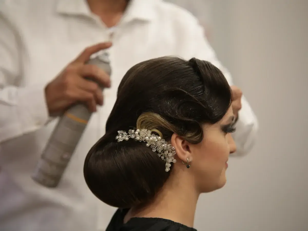 Illustrative photo of a hairstylist applying a styling spray can to a client's updo, not the actual recalled Schwarzkopf Osis Grip mousse